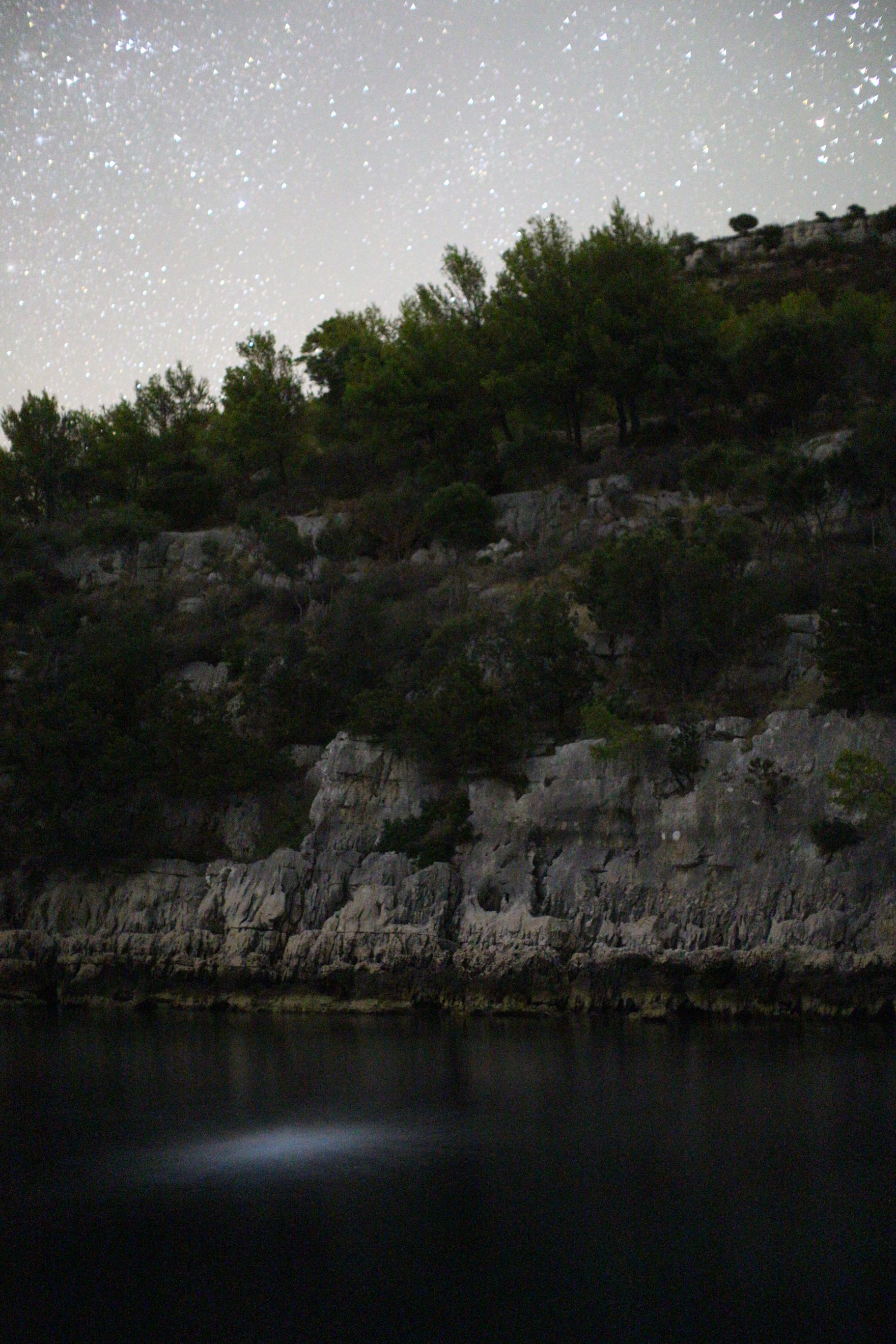 Lastovo, Croatia - stars with bioluminiscent plankton and reflection of stones and stars in water of Skrivena Luka MR